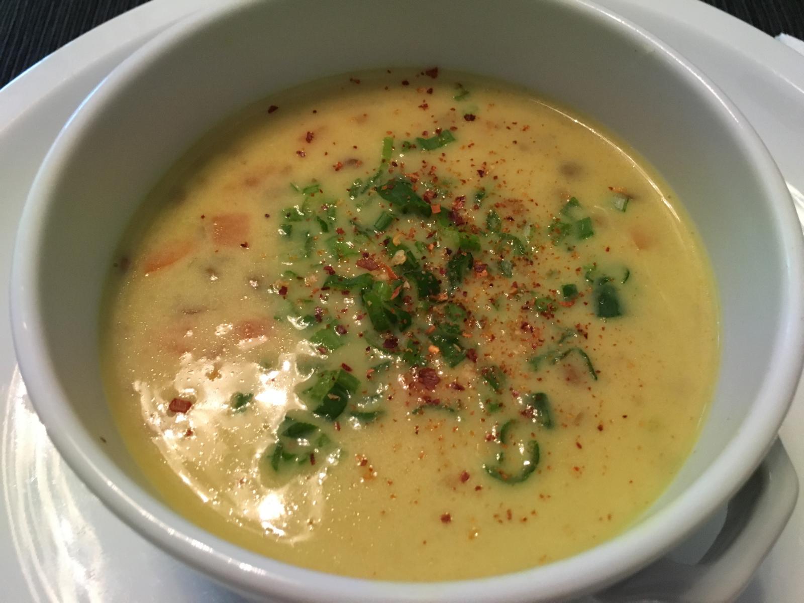 Linsensuppe nach Thai-Art wird vorm Servieren mit Frühlingszwiebelgrün und Chili bestreut